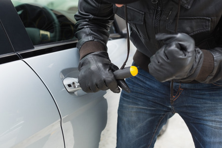 Thief breaking into car with screwdriver in broad daylight