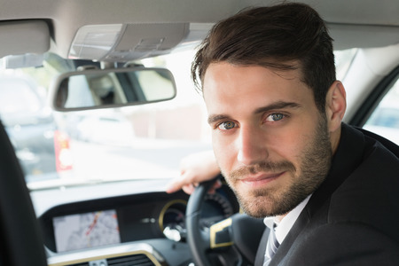Young businessman looking at camera in his carの写真素材