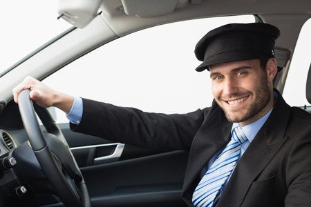 Handsome chauffeur smiling at camera in the car