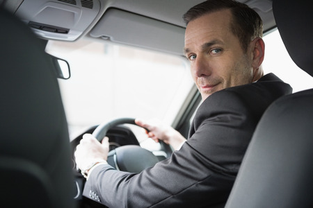 Handsome businessman looking at camera in his car