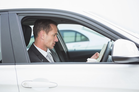 Serious businessman reading a map in his car