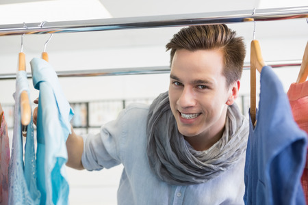 Smiling student near clothes rack at the collegeの写真素材