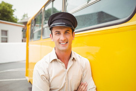 Smiling bus driver looking at camera outside the elementary schoolの写真素材