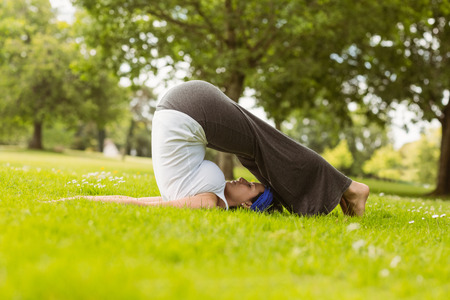 Brown hair doing yoga on grass in the parkの写真素材