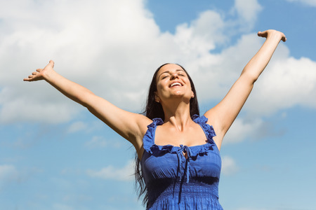 Smiling brunette in blue dress feeling free on a sunny dayの写真素材