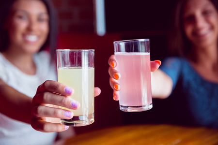Happy friends toasting to camera in a barの写真素材