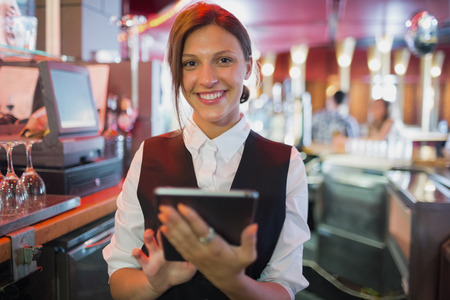 Focused barmaid using touchscreen till in a bar