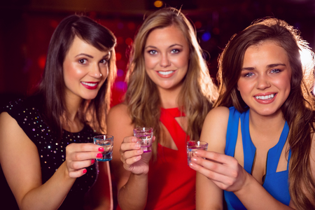 Pretty friends drinking shots together at the nightclubの写真素材