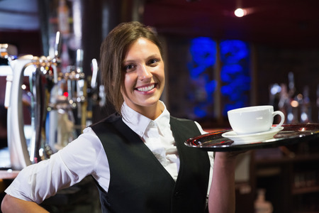 Happy barmaid holding tray with coffee in a barの写真素材