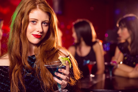 Pretty redhead drinking a cocktail at the nightclubの写真素材