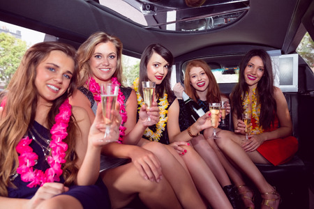 Happy friends drinking champagne in limousine on a night out