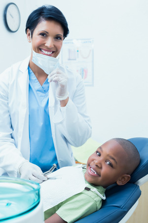 Portrait of smiling female dentist examining boys teeth in the dentists chairの写真素材