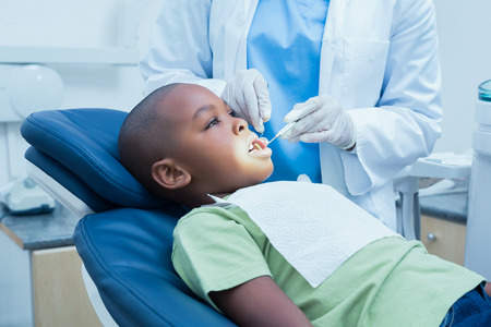 Side view of boy having his teeth examined by a dentistの写真素材