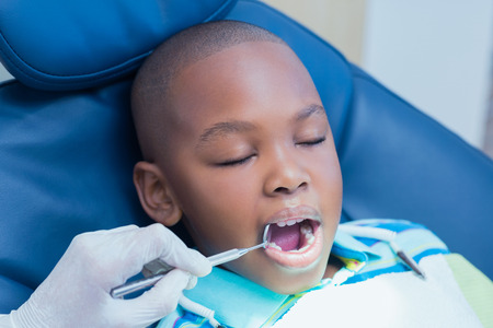 Close up of boy having his teeth examined by a dentistの写真素材