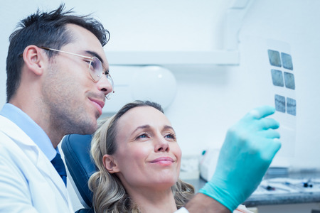 Side view of male dentist showing woman her mouth x-rayの写真素材