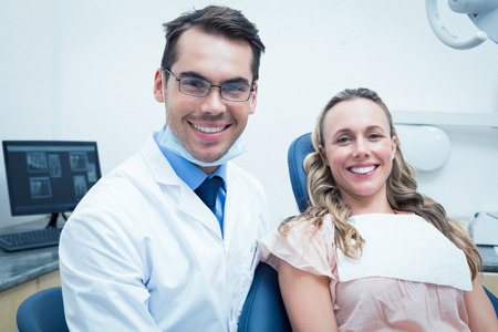 Dentist examining young womans teeth in the dentists chairの写真素材