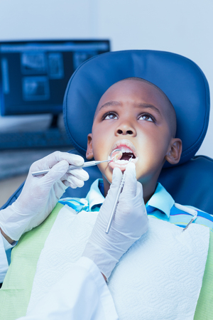 Close up of boy having his teeth examined by a dentistの写真素材