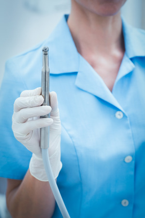 Close up mid section of female dentist holding dental drillの写真素材