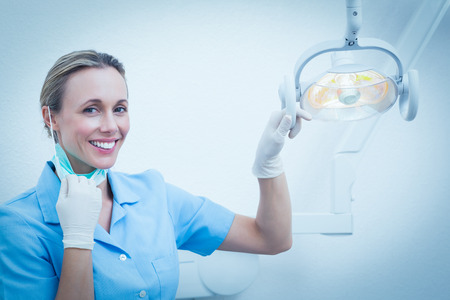 Portrait of smiling female dentist adjusting lightの写真素材