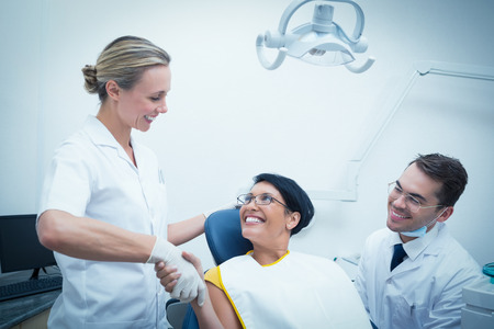 Female dentist shaking hands with woman in the dentists chairの写真素材