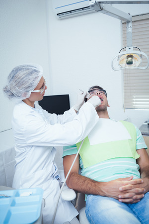 Female dentist examining mans teeth in the dentists chairの写真素材