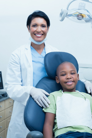 Portrait of female dentist examining boys teeth in the dentists chairの写真素材