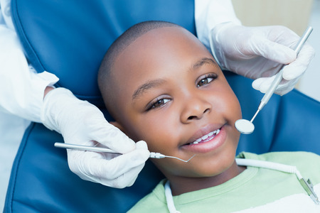 Close up of boy having his teeth examined by a dentistの写真素材