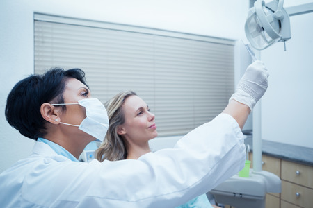 Side view of female dentist showing woman her mouth x-rayの写真素材