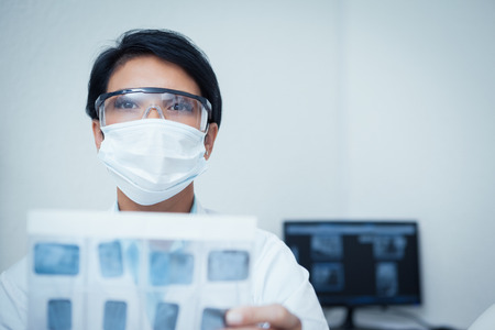 Portrait of serious young female dentist holding x-rayの写真素材