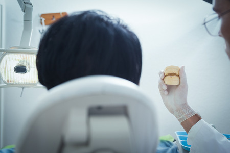 Dentist showing woman model teeth in the dentists chairの写真素材