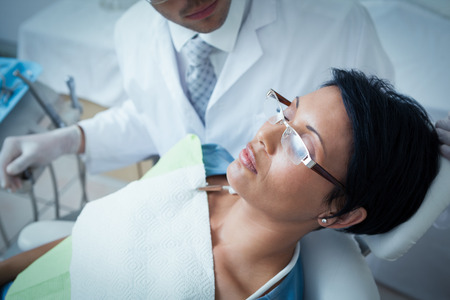 Male dentist examining womans teeth in the dentists chairの写真素材