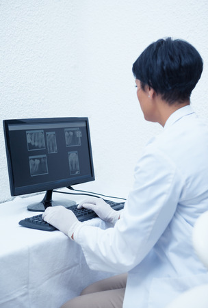 Concentrated female dentist looking at x-ray on computerの写真素材