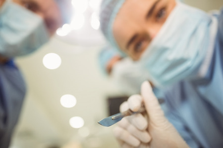 Young surgeons looking down at camera holding scalpel at the universityの写真素材