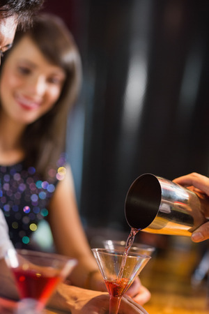 Bartender pouring cocktail for customers at the nightclubの写真素材