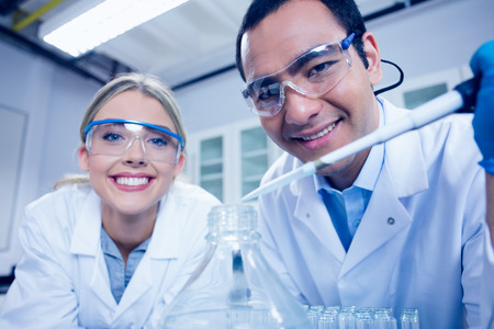 Science students using pipette to fill beaker at the universityの写真素材