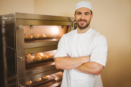 Baker smiling at camera beside oven in a commercial kitchenの写真素材