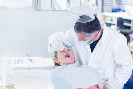 Dentist examining a patients teeth in the dentists chair at the dental clinicの写真素材