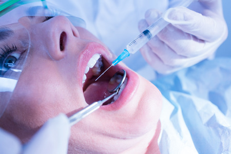 Dentist about to give injection to terrified patient at the dental clinicの写真素材