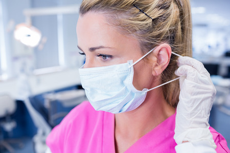 Dentist putting on her surgical mask at the dental clinicの写真素材