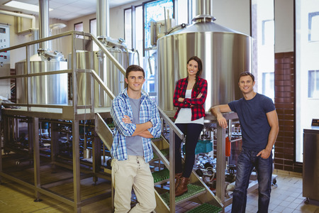 Happy hipster smiling at camera together in the factory