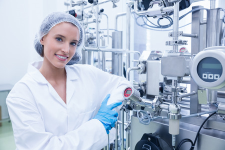 Smiling scientist leaning against gauge in the factory