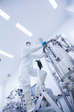 Scientist standing on ladder looking at the camera in the factory