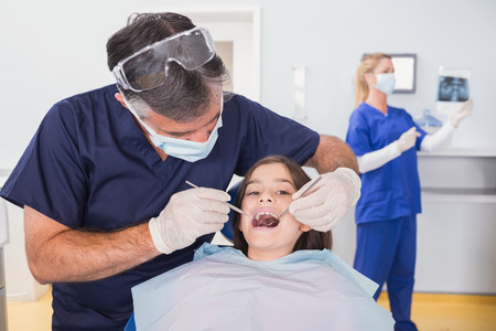 Pediatric dentist examining her young patient in dental clinicの写真素材