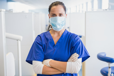 Dentist wearing surgical mask with arms folded in dental clinicの写真素材