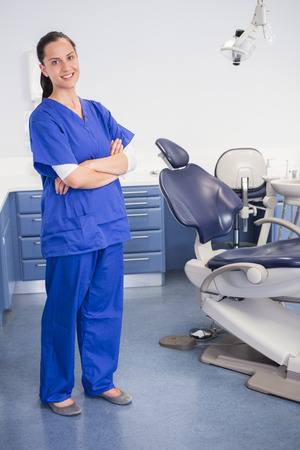 Cheerful dentist standing with arms crossed in dental clinicの写真素材