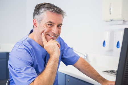 Portrait of a smiling dentist using computer in dental clinicの写真素材