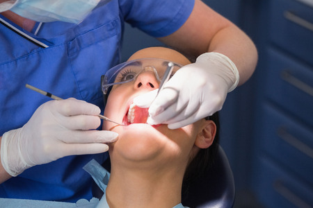 Dentist examining a patient with angle mirror and sickle probe in dental clinic