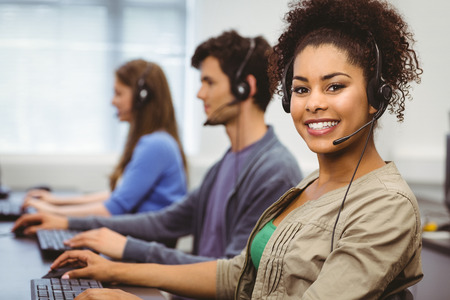 Smiling student with headset using computer at the universityの写真素材