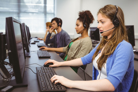 Student sitting at the computer room wearing headset at the universityの写真素材
