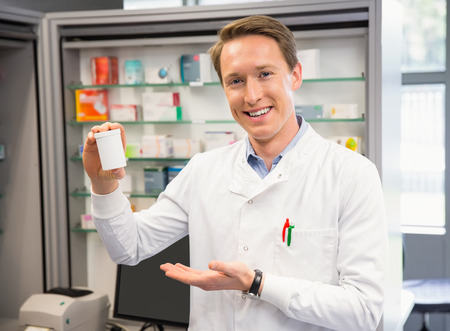 Handsome pharmacist showing medicine jar at the hospital pharmacyの写真素材